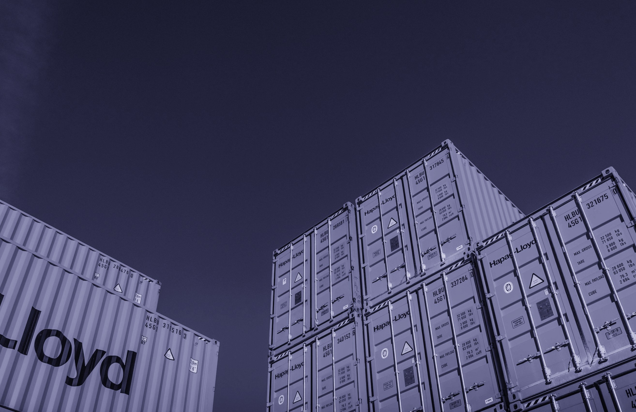 Stacked Hapag-Lloyd shipping containers at a port yard
